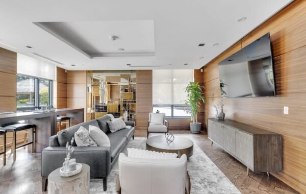 Party room lounge with grey sofa, wood panelling, wall-mounted TV and bar seating at 21 Clairtrell