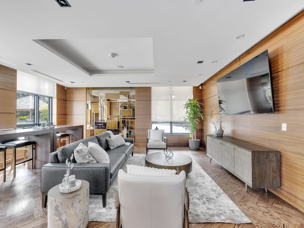 Party room lounge with grey sofa, wood panelling, wall-mounted TV and bar seating at 21 Clairtrell