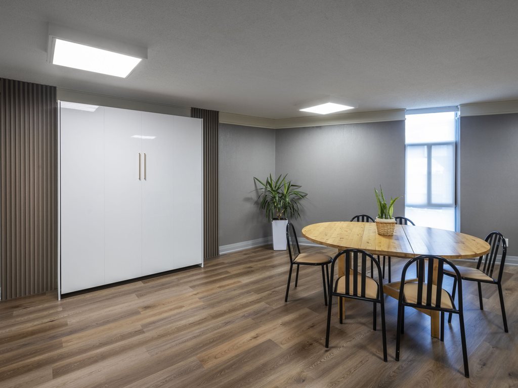 Renovated 250 Queens Quay party room and guest suite with a closed Murphy bed, round dining table and wood-look floor