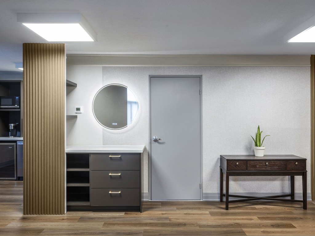 Guest suite wall at 250 Queens Quay with a backlit round mirror, vanity drawers and wood slat panelling