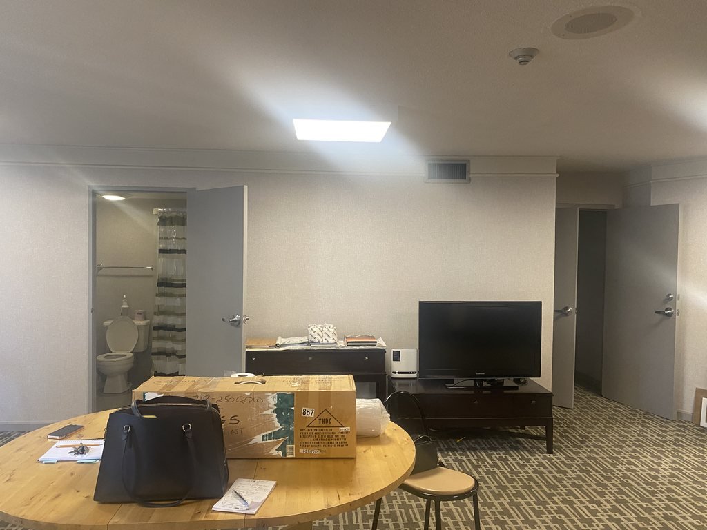 250 Queens Quay party room before renovation with a round table, TV and patterned carpet