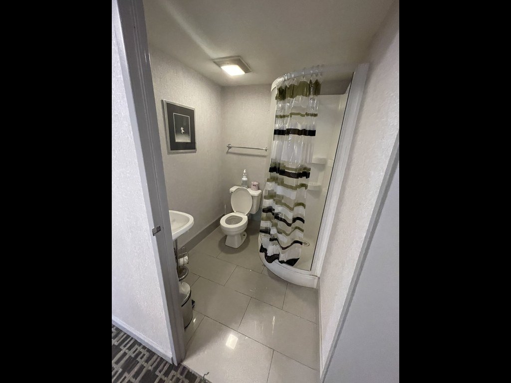 Old bathroom at 250 Queens Quay before renovation with a patterned shower curtain