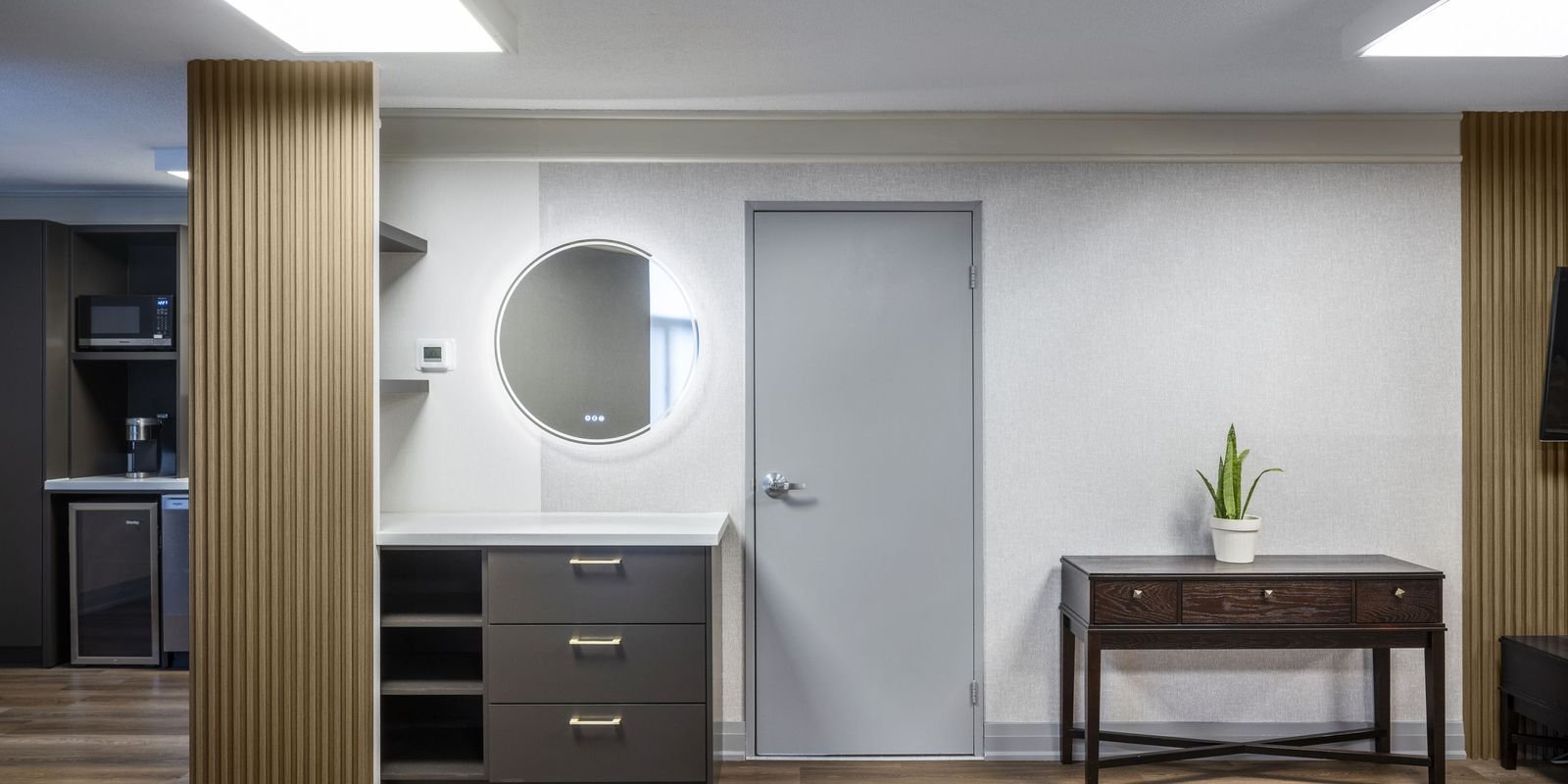 250 Queens Quay guest suite after renovation with backlit round mirror, vanity and wood slat panelling
