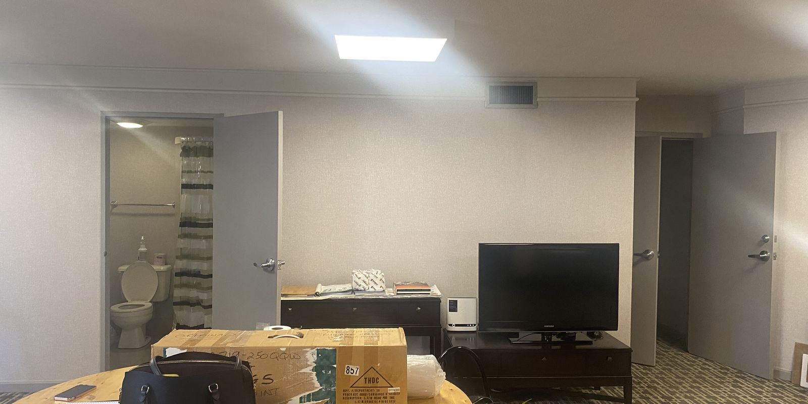 250 Queens Quay party room before renovation with a TV, round table and open bathroom door