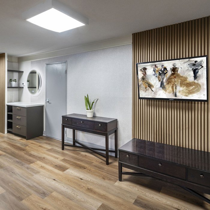 Wood-slat feature wall with framed artwork, console table and bench in the renovated 250 Queens Quay suite
