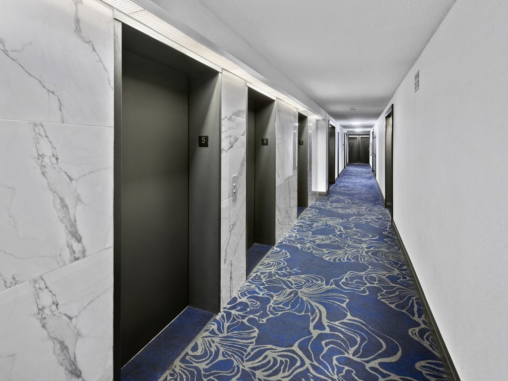 Marble-look tile elevator landing and dark doors along the Platinum on The Humber II corridor