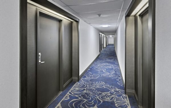 Long Platinum on The Humber II corridor with dark suite doors, light walls and custom blue carpet