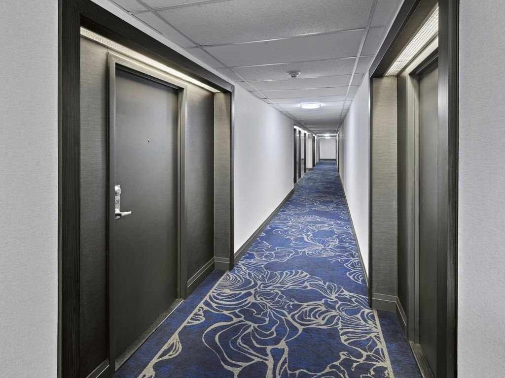 Long Platinum on The Humber II corridor with dark suite doors, light walls and custom blue carpet