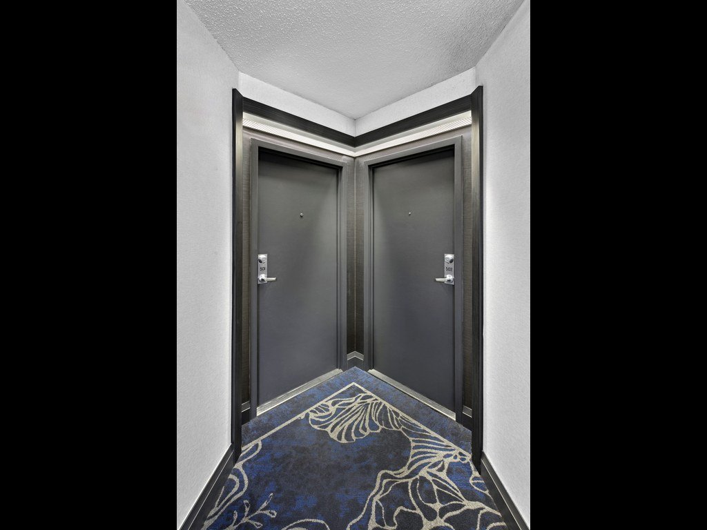 Pair of dark suite doors meeting at a corridor corner at Platinum on The Humber II