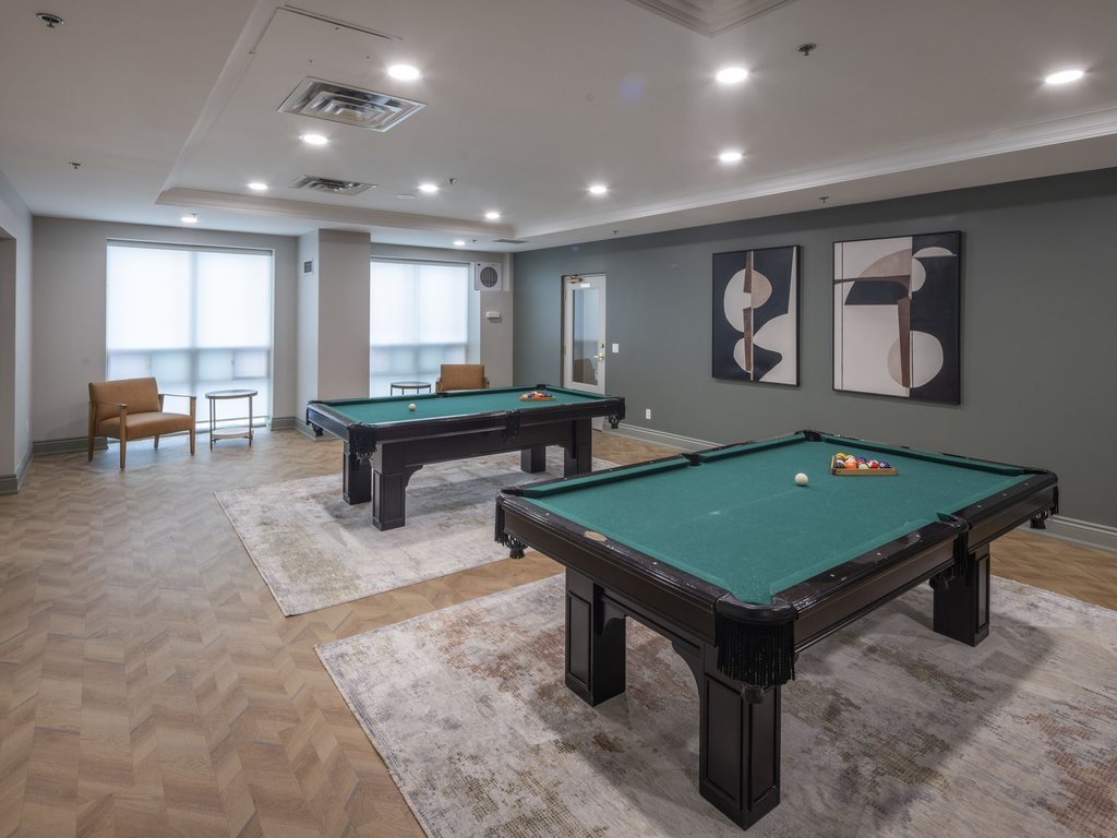 Two green pool tables on area rugs in the renovated 7 & 9 Michael Power billiards room