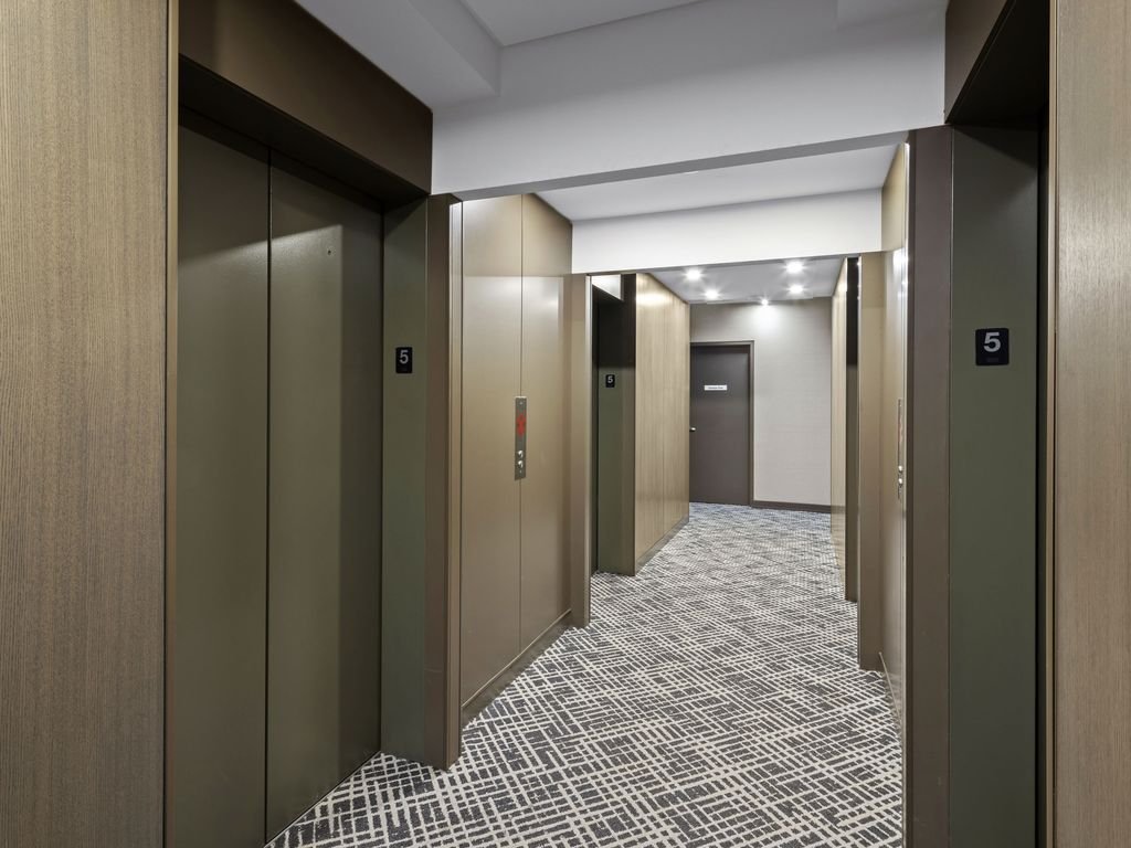 X2 Condos hallway with new patterned carpet, warm bronze panelling and elevator doors