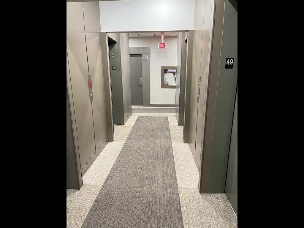 X2 Condos corridor before refurbishment with a grey runner carpet and pale borders
