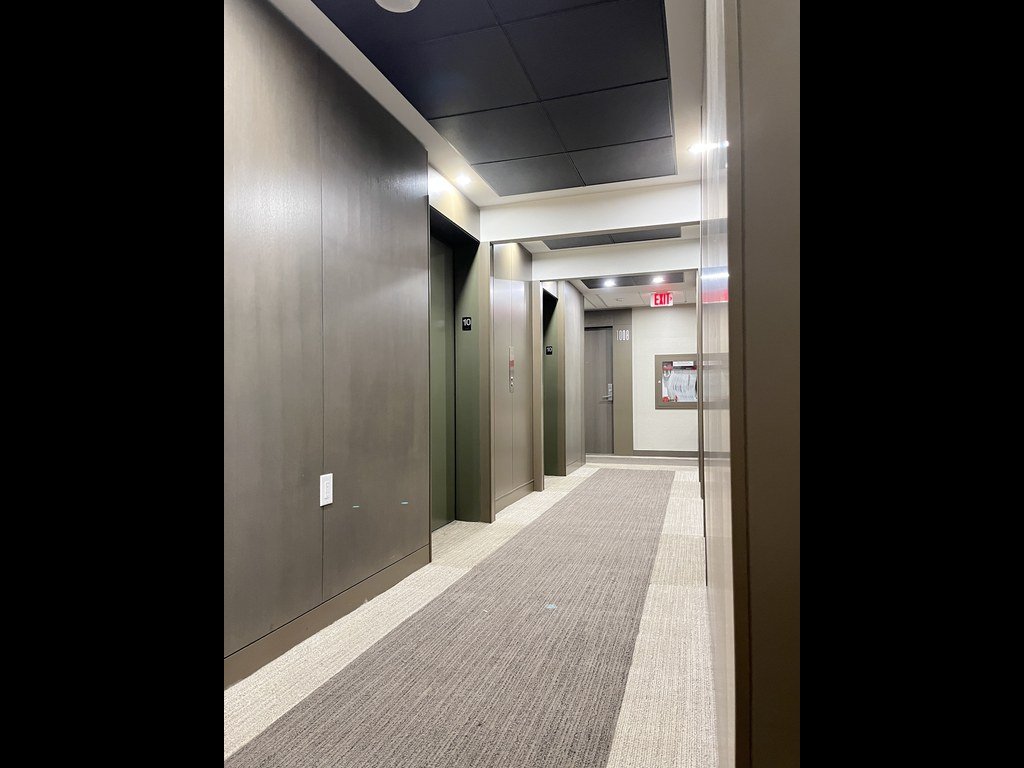 Dark panelled wall and elevator lobby in the X2 Condos corridor before refurbishment